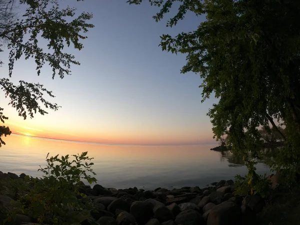 Красивый Вид Море Окруженное Деревьями Закатным Небом — стоковое фото