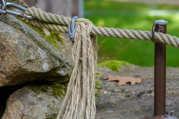 A closeup of a rope tied to fences in a park oputdoors