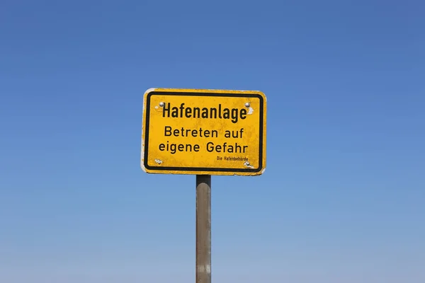 青い空に対してドイツ語で警告テキストを持つ記号ポール — ストック写真