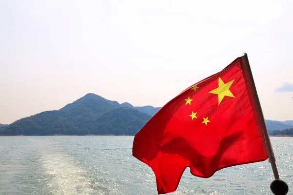 水平線の山と海の近くに手を振って中国の国旗のクローズアップショット — ストック写真