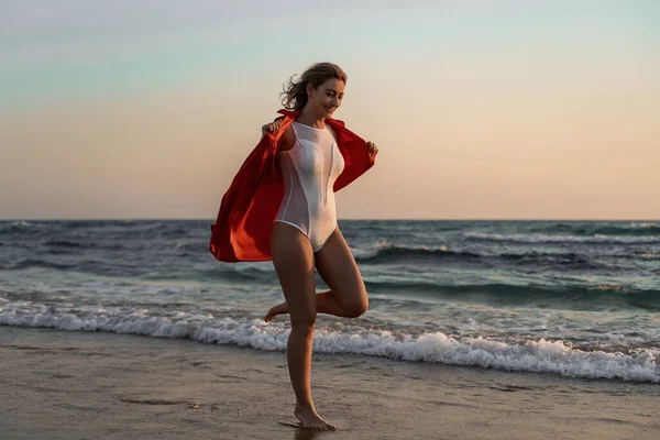 一个性感的白人女人 身穿白色泳衣 日落时穿着衬衫在海滩上摆姿势 — 图库照片