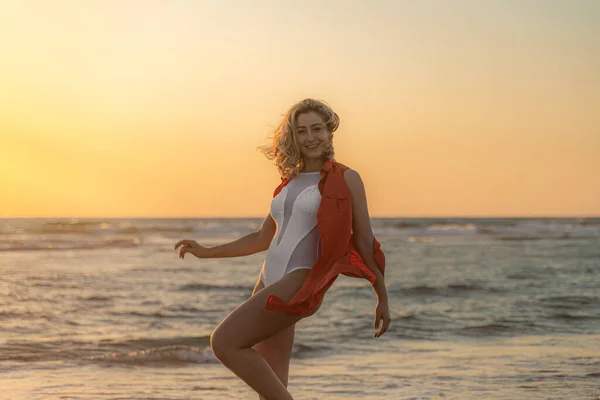 白い水着を着たセクシーな白人女性と日没時にビーチにポーズをとるシャツ — ストック写真