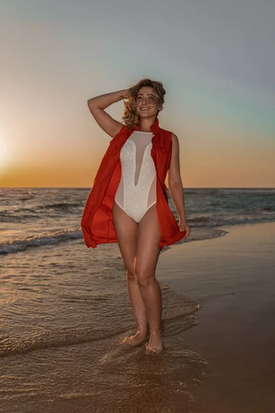 日没時に海岸で白人の若い女性の垂直ショット — ストック写真
