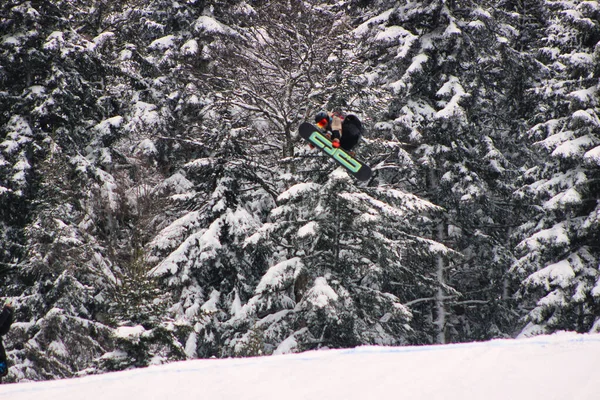 Ένας Snowboarder Πηδάει Πάνω Από Μια Χιονισμένη Πλαγιά — Φωτογραφία Αρχείου