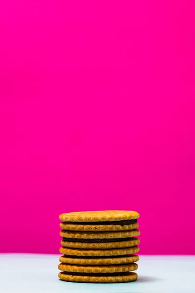 ピンクの背景にチョコレートクリームと丸いビスケットのクローズアップショット — ストック写真