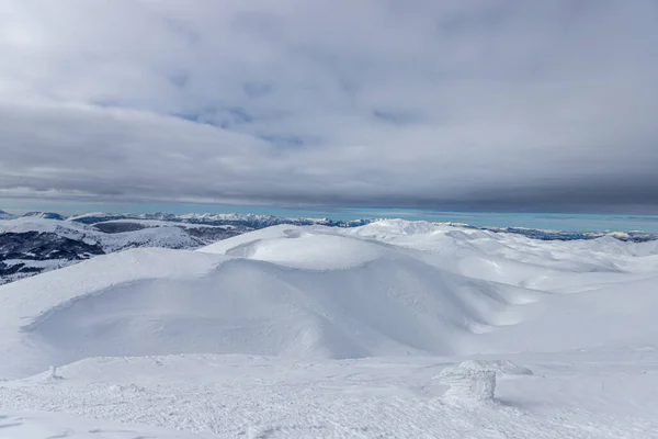 Kırsalda Bulutlu Bir Gökyüzünün Altında Karla Kaplı Tepelerden Oluşan Bir — Stok fotoğraf