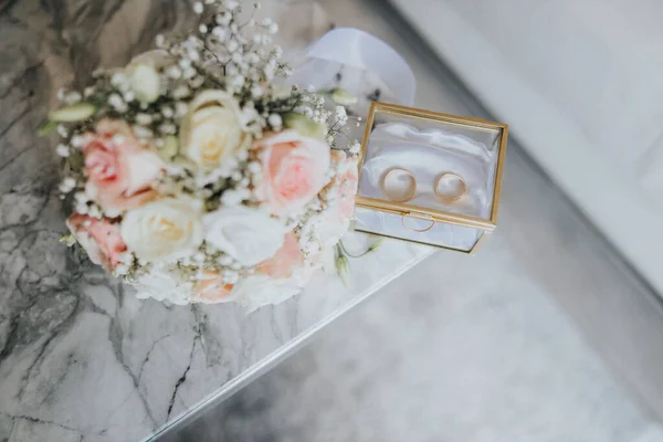 这对夫妇的金戒指和桌上的新娘花束 — 图库照片