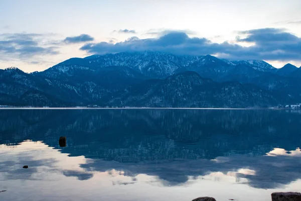 Piękne Jezioro Woda Odzwierciedlająca Śnieżne Góry Tle Zachmurzone Niebo — Zdjęcie stockowe