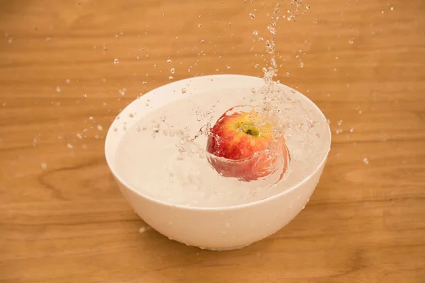 Sebuah Apel Percikan Dalam Mangkuk Air Atas Meja Kayu — Stok Foto