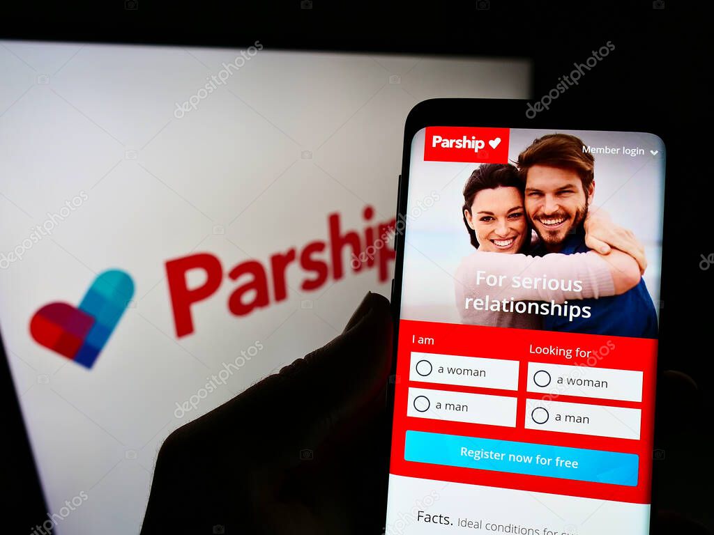 STUTTGART, GERMANY - Dec 12, 2021: Person holding cellphone with webpage of online dating company ParshipMeet Holding GmbH on screen with logo. Focus on center of phone display.