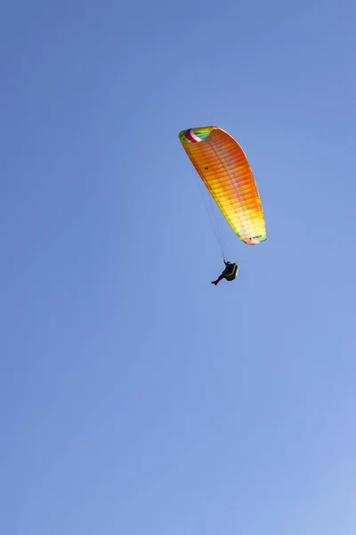 Açık Mavi Gökyüzüne Karşı Renkli Bir Paraşütle Uçan Bir Paraglider — Stok fotoğraf