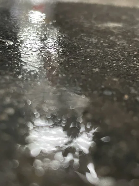 道路上の水溜りに反射する太陽光の垂直ショット — ストック写真