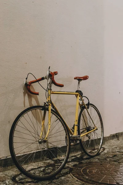 停在墙边的一辆黄色自行车的垂直镜头 — 图库照片
