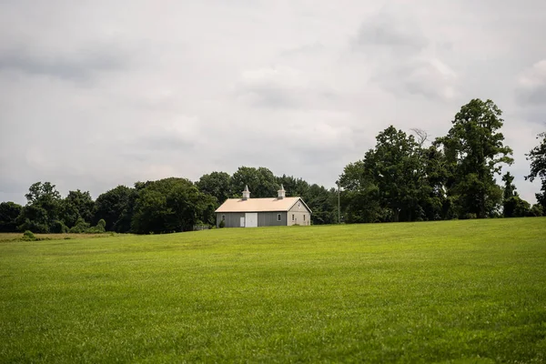 Een Grote Groene Weide Met Een Huisje Bomen Achtergrond — Stockfoto