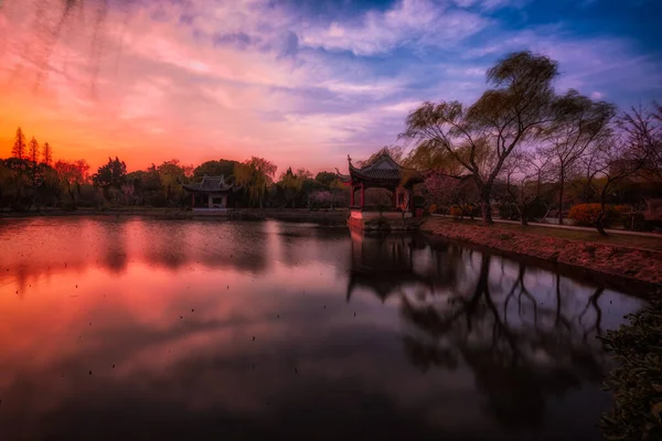 一座中国塔 座落在风景秀丽的湖畔 映衬着五彩缤纷的夕阳天 — 图库照片