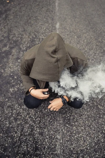 Svislý Záběr Kouřícího Muže Kapucí Dřepící Venku Ulici — Stock fotografie