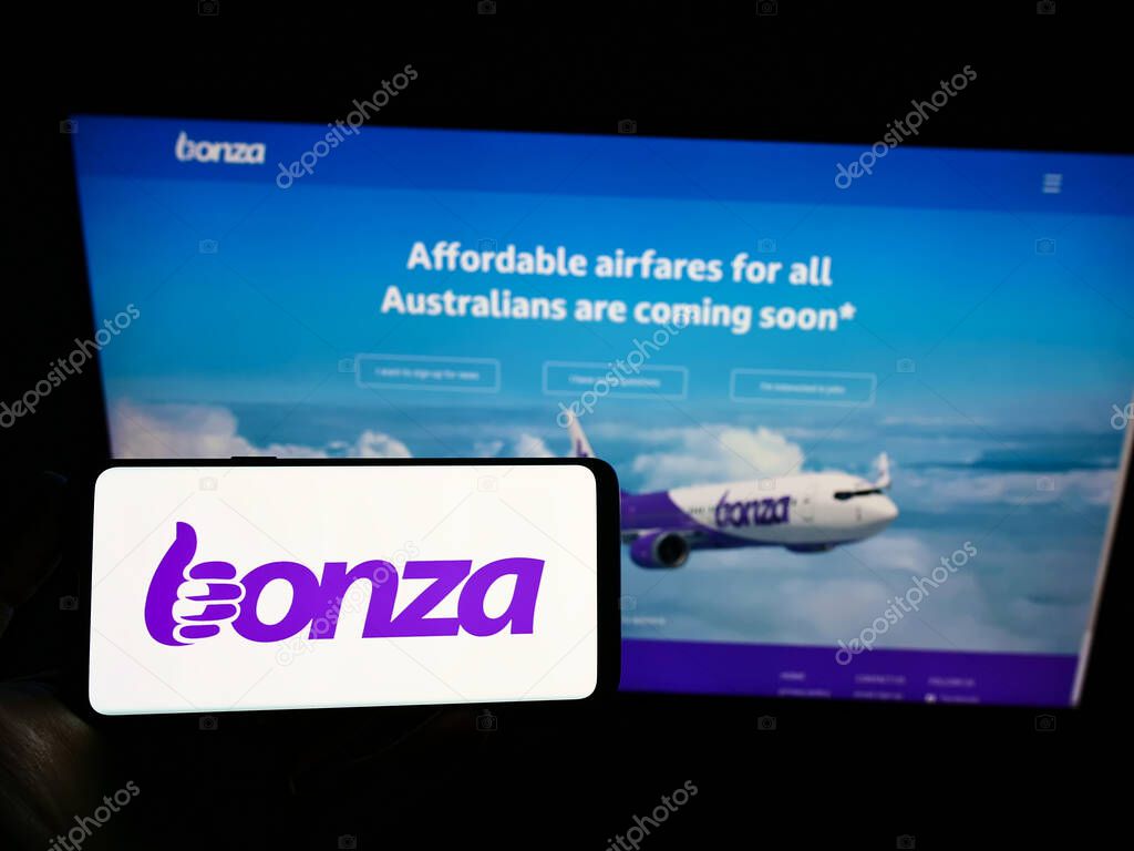 STUTTGART, GERMANY - Dec 13, 2021: Person holding smartphone with logo of Australian airline Bonza Aviation Pty Ltd. on screen in front of website. Focus on phone display.