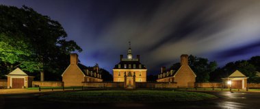 The illuminated Governor's Palace against a cloudy sky at night in Williamsburg, Virginia, USA clipart