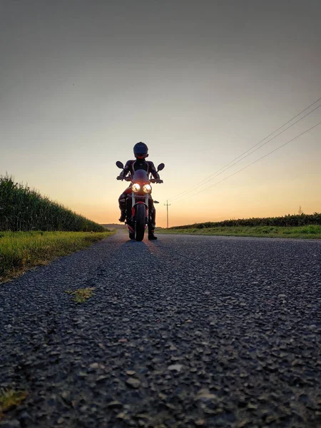 在日落背景下骑摩托车的人的垂直照片 — 图库照片