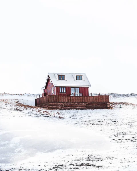 昼間の雪景色の中の赤い家の垂直ショット — ストック写真