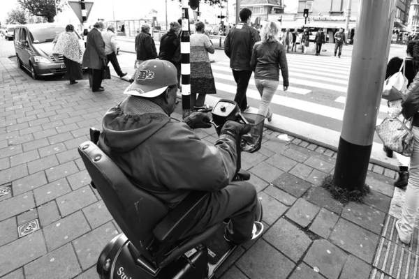 一个坐在轮椅上的男子试图穿过街道的灰白色比例 — 图库照片