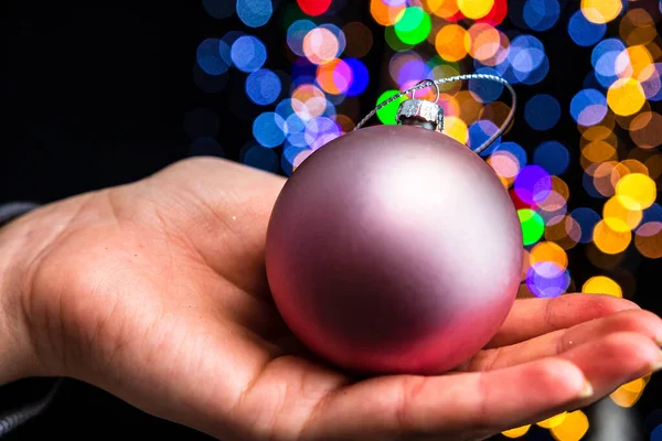 Eine Person Hält Weihnachtskugeldekoration Vor Bokeh Licht Hintergrund — Stockfoto