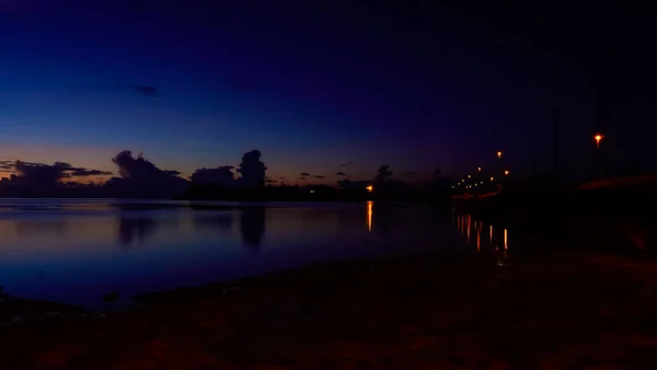 Klidná Jezerní Voda Odrážející Nedaleká Venkovní Světla Zatažená Obloha Při — Stock fotografie