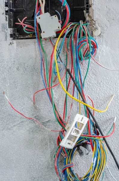 Вертикальный Снимок Электрических Несвязанных Цветных Проводов Исходящих Белой Стены — стоковое фото