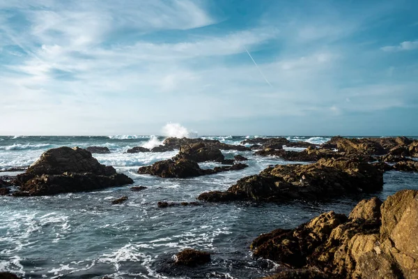 Bulutlu Bir Gökyüzüne Karşı Sıçratan Deniz Dalgaları Üzerindeki Kaya Oluşumlarının — Stok fotoğraf