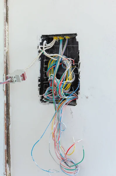 Вертикальный Снимок Электрических Несвязанных Цветных Проводов Исходящих Черной Дыры Белом — стоковое фото