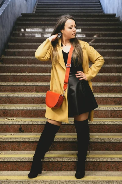 火车站楼梯上 一个身穿黄色外套和黑色裙子的年轻女子的垂直镜头 — 图库照片