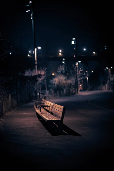 Вертикальный Снимок Деревянной Скамейки Обочине Дороги Ночью — стоковое фото