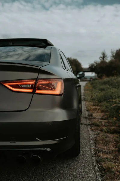 Een Verticaal Schot Van Een Matte Zwarte Auto Geparkeerd Buurt — Stockfoto