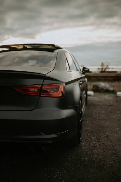 Vertical Shot Matte Black Car Parked Road Cloudy Skies — Stock Photo, Image