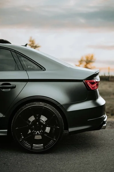 Вертикальний Знімок Матового Чорного Автомобіля Припаркованого Біля Дороги Під Хмарним — стокове фото