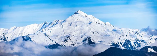 Een Panoramisch Shot Van Besneeuwde Bergtoppen Onder Een Blauwe Lucht — Stockfoto