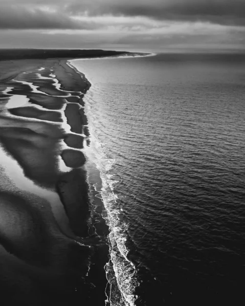 Vertikální Snímek Pláže Stupních Šedi Krásnými Mořskými Vlnami Pod Zamračenou — Stock fotografie
