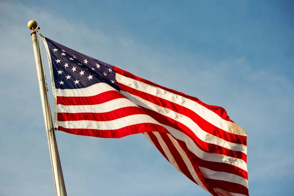 晴れた日に青い曇り空に向かって手を振っているアメリカ国旗のクローズアップショット ストック写真
