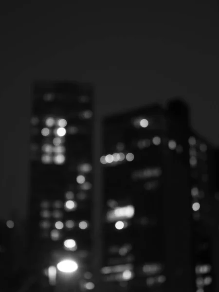 Pionowe Ujęcie Skali Szarości Pięknych Wysokich Budynków Rozmazane Nocą — Zdjęcie stockowe