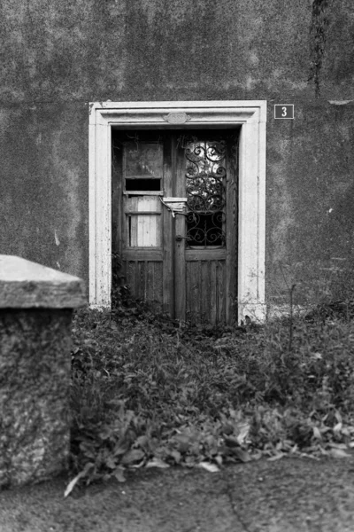 Pionowe Czarno Białe Ujęcie Starych Drewnianych Prawie Zmiażdżonych Drzwi — Zdjęcie stockowe