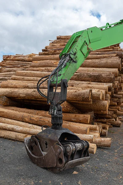 A vertical shot of Green machine for transporting logs and piles of felled trees for the timber industry.