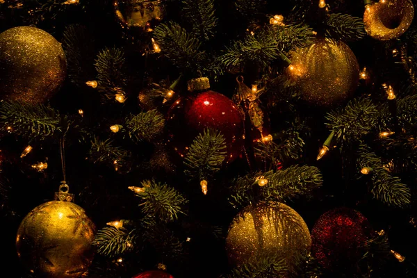 輝く光のツリー上の美しい光沢のある赤と黄色のクリスマスボールのクローズアップショット — ストック写真