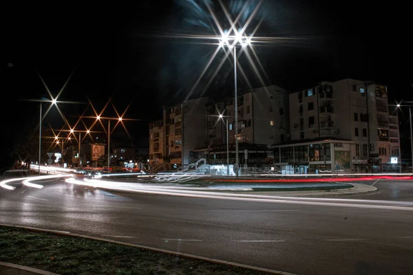 ライトアップされた町と長い露出車が真夜中に一周します — ストック写真