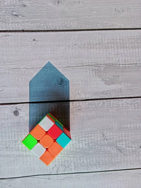 A unsorted puzzle-box in sunlight. The object is placed in a wooden surface and the sunlight created a triangular top shadow