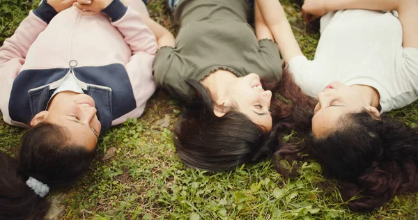 公園で草の上に寝そべっている幸せな若い女性のグループ — ストック写真