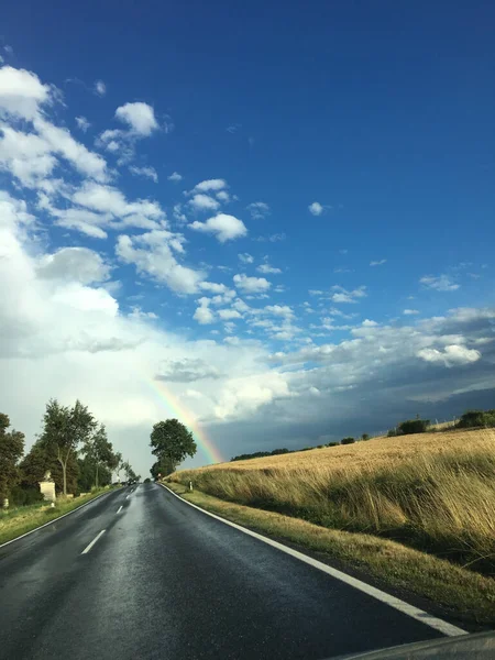 stock image A vertical shot of a highway and rainbow in the sky