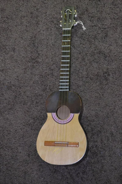 Eine Vertikale Aufnahme Einer Gitarre Auf Einer Grauen Oberfläche — Stockfoto