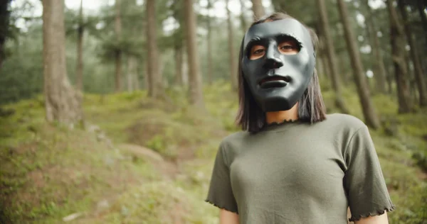 一个身穿黑衣 戴着面具的年轻女子在森林里 — 图库照片
