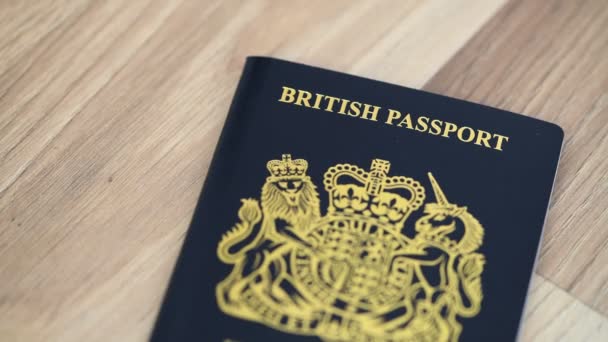 木製のテーブルの上に英国のパスポートのクローズアップ映像 — ストック動画