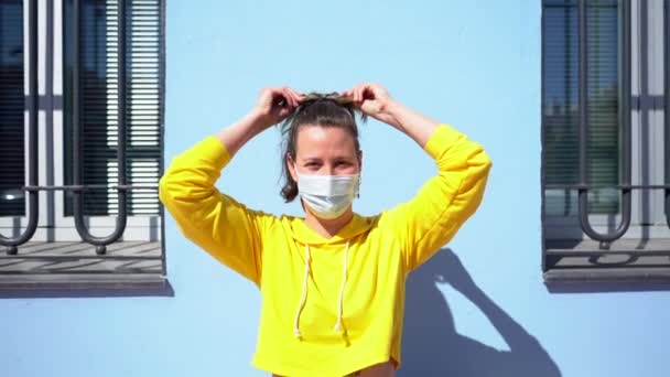 青い壁の背景に保護マスクをした若い女性が — ストック動画